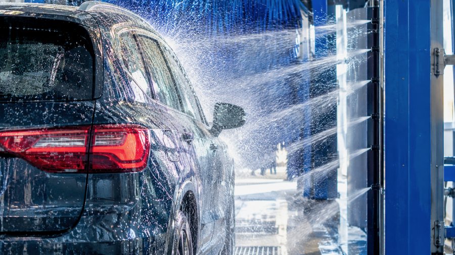 A car passing through an automatic wash tunnel under high-pressure jets